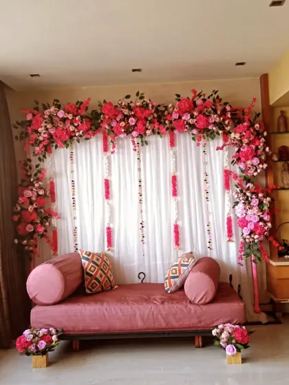 A vibrant engagement or roka decoration done at home. I created a backdrop with a curtain of fairy lights and a full arch of bright pink flowers.