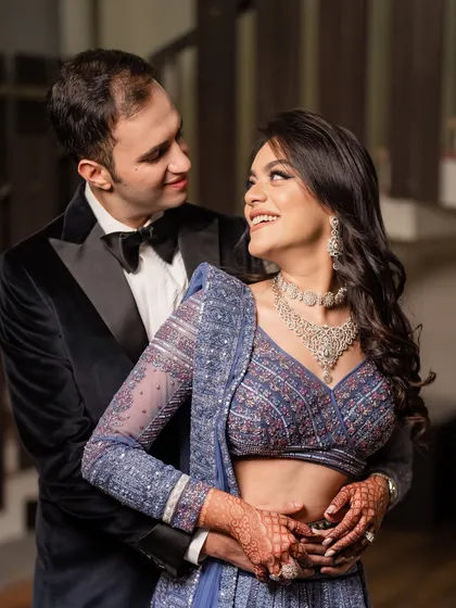 An intimate portrait of a couple, with the groom embracing the bride from behind, both sharing a look of love and happiness.