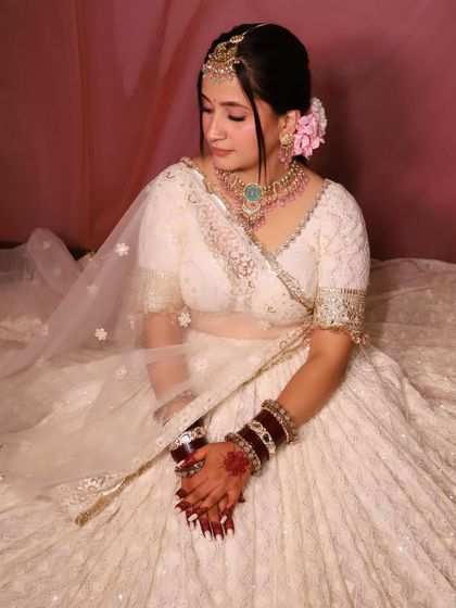 A serene and elegant portrait of the bride. The soft makeup and pink floral hair accessory add a touch of romance.