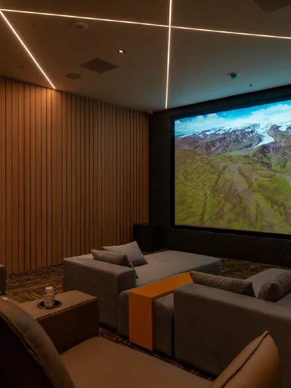 A look inside one of our showroom's demonstration theaters. This space combines modern aesthetics with high-performance technology, featuring wood-paneled acoustic walls, recessed ceiling speakers for Dolby Atmos, and a mix of sofa and recliner seating.