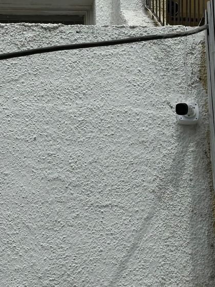 A bullet camera installed on a textured exterior wall. We ensure the mount is secure regardless of the surface, providing a stable base for the surveillance equipment.