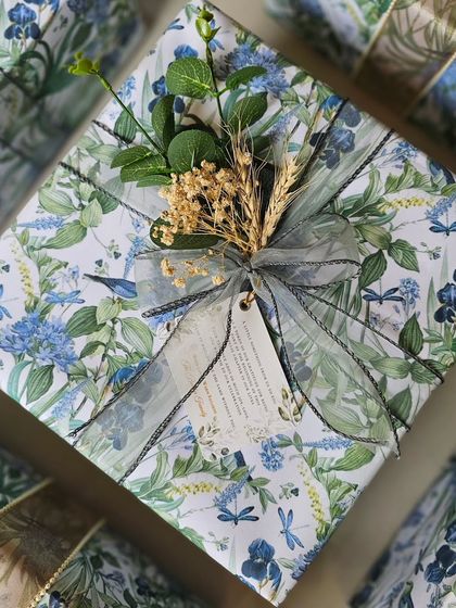 Custom-made gift wrapping paper for these beautiful wedding return favors. The delicate blue and green floral print is complemented by an elegant organza ribbon and a sprig of dried botanicals.