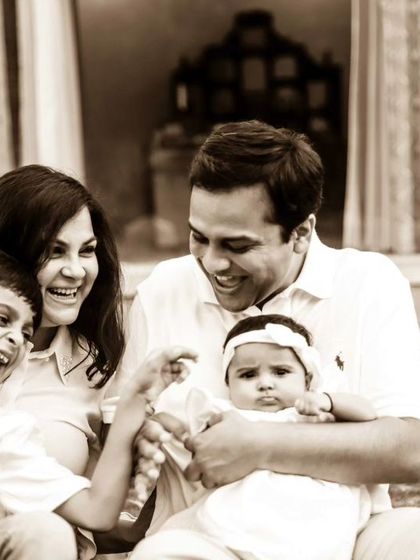 A sepia-toned photo capturing a burst of laughter from the whole family during their outdoor session. It's never too late to capture these moments.