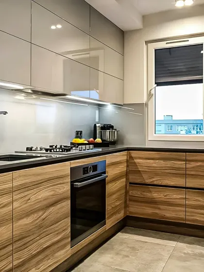 This L-shaped modular kitchen features a dual-tone design with high-gloss grey upper cabinets and warm wood-grain lower units. We've integrated under-cabinet LED lighting for task illumination and built-in appliances for a seamless, modern look.