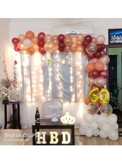Celebrating a 60th birthday at home with a simple and elegant setup. This decor features a beautiful balloon arch, a '60' foil balloon, and 'HBD' marquee letters, proving that milestone birthdays can be celebrated beautifully anywhere.