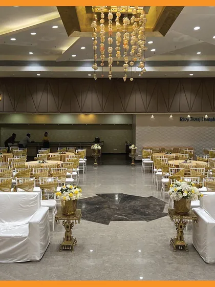 A view of the banquet hall ready for a Mehendi, with elegant chandeliers and organized seating, ready to welcome guests.