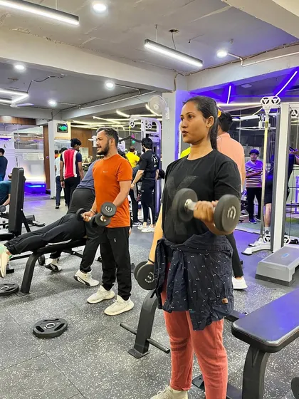 Dedication, discipline, and consistency are what you'll find at our gym every day. Here, members are focused on their dumbbell workouts.