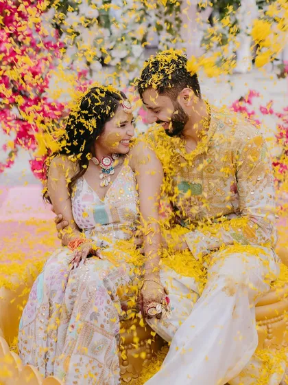 The pure bliss of a Haldi ceremony, as the couple is showered with a cascade of yellow flower petals, their faces lit up with laughter and joy.
