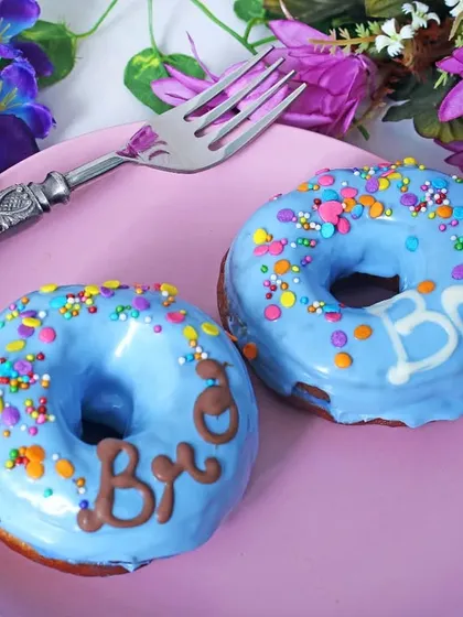 Two blue-frosted donuts with colorful sprinkles, styled with purple flowers. This playful and bright setup is perfect for a fun, youthful brand targeting social media engagement.