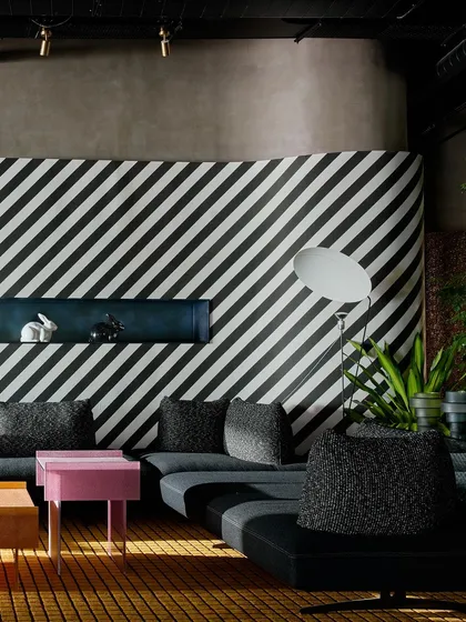 A closer view of the graphic striped wall and modular sofa. The built-in shelf adds a block of color, while the oversized floor lamp provides sculptural lighting.