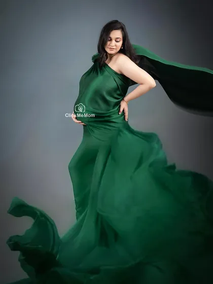 A powerful pose in a flowing emerald green satin gown. The movement of the fabric adds a dynamic and artistic element to this maternity photo, showcasing both strength and grace.