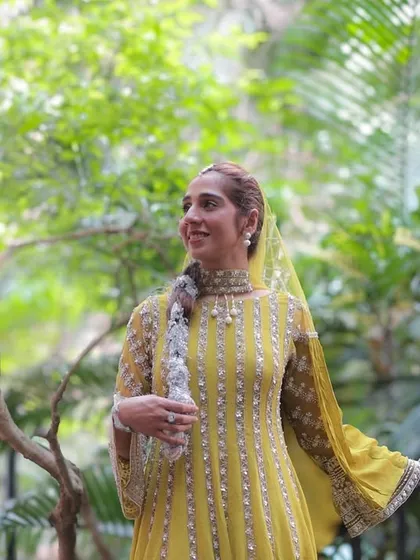 A bride enjoying a moment in a lush, green setting during her pre-wedding festivities. Her yellow outfit glows in the natural light, making for a beautiful, relaxed portrait.