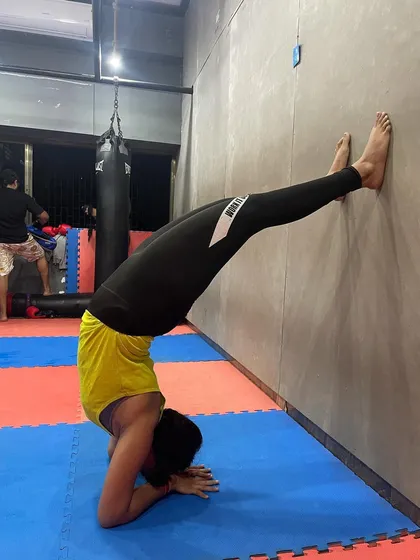 A client practicing a forearm headstand against the wall. Inversions like this are great for building upper body strength, improving balance, and can be a part of our yoga-inspired cool-downs.