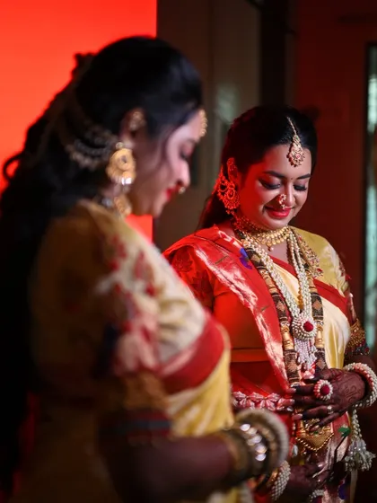 A candid moment from a baby shower. The mom-to-be is wearing a traditional red and white floral set, perfectly matching her beautiful yellow and red saree.
