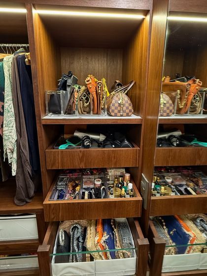 A close-up of a beautifully organized section in a wooden walk-in closet, showing how we store bags, accessories, and folded items in a way that is both visible and protected.