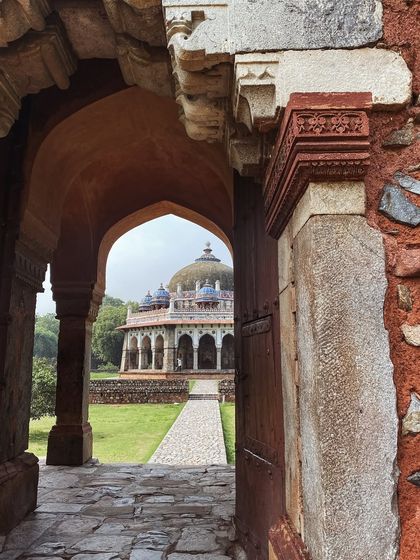 A view of Isa Khan's tomb framed through an ancient stone archway at the Humayun's Tomb complex.