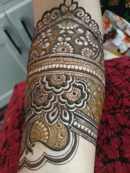 A close-up of an armband section of a bridal design, showing the intricate floral and geometric details.