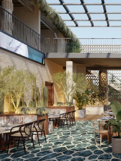 The double-height atrium at Skyro, with its glass ceiling, allows natural light to flood the space. The green stone floor and abundant plants create the feeling of a luxurious, open-air courtyard.