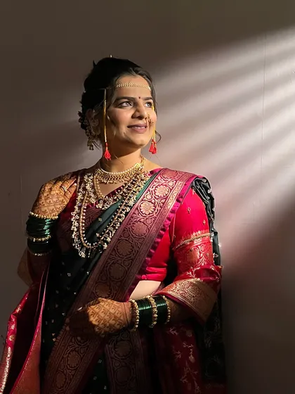 A beautifully lit shot of the bride, highlighting the soft makeup and the intricate details of her jewellery and saree.