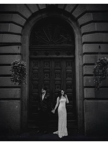 A dramatic black and white version of the couple standing before the ornate door, emphasizing contrast and form.