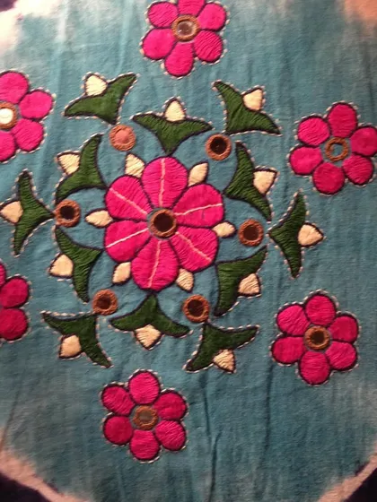 This vibrant floral medallion with mirror work is an example of the rich embroidery traditions of Gujarat. The bright colors and shimmering mirrors create a joyful effect.