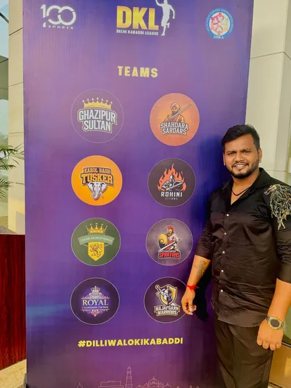 Posing next to the banner showcasing the teams of the Delhi Kabaddi League.