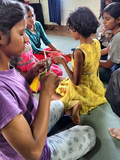 Girls work together on a craft activity, cutting and folding paper. Even after Diwali, the joy of creating something beautiful with their own hands still shines brightly.