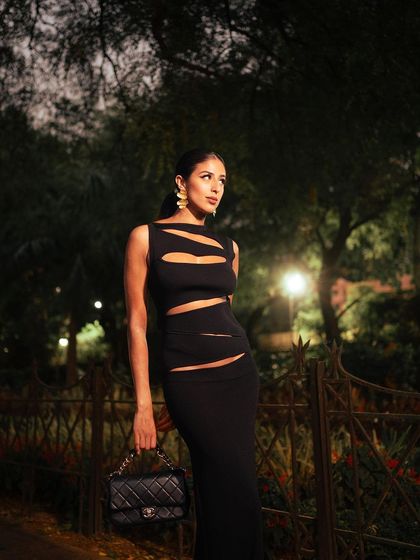 A full-length shot showcasing the entire Christopher Esber dress and Chanel bag. The composition and lighting are designed to create a sophisticated and aspirational lifestyle image.
