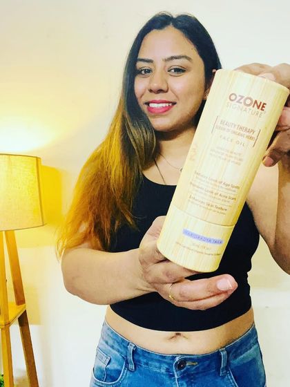 Holding up the Ozone Signature Haridradya Taila, an Ayurvedic serum designed to combat acne and scars. This is my go-to for a clear complexion.