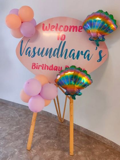 A simple yet elegant welcome sign for Vasundhara's mermaid-themed party, adorned with iridescent shell balloons.