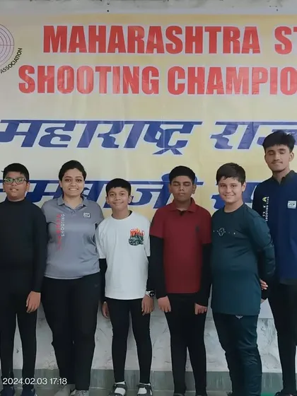 A coach stands proudly with his team of young male shooters at the Maharashtra State Shooting Championship. My coaches are partners in our athletes' journeys, present at every competition.