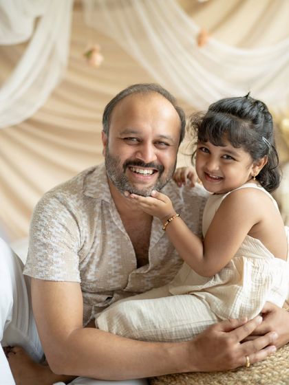 A father and daughter share a playful moment. Her hand on his chin is such a sweet detail.