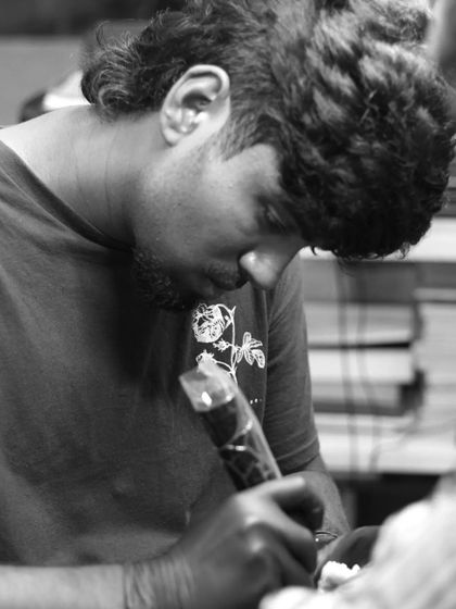 A black and white shot of one of our artists focused on his work. We are dedicated to the art and craft of tattooing.