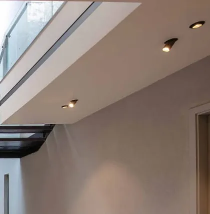 A detail of minimalist ceiling spotlights and the clean junction between the wall and a floating balcony edge.