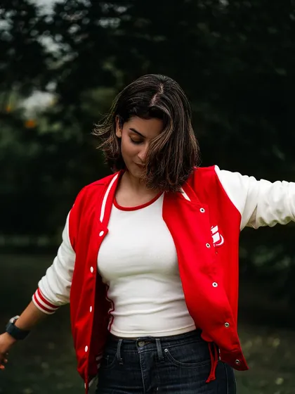 A candid, joyful shot of a model in a red and white varsity jacket, captured mid-motion. This style of image shows personality and is great for lifestyle or commercial work.