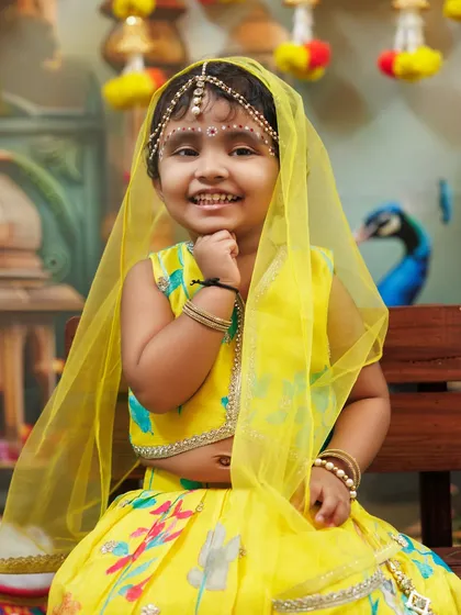 A beautiful smile from a little girl dressed as Radha, with a delicate yellow veil.