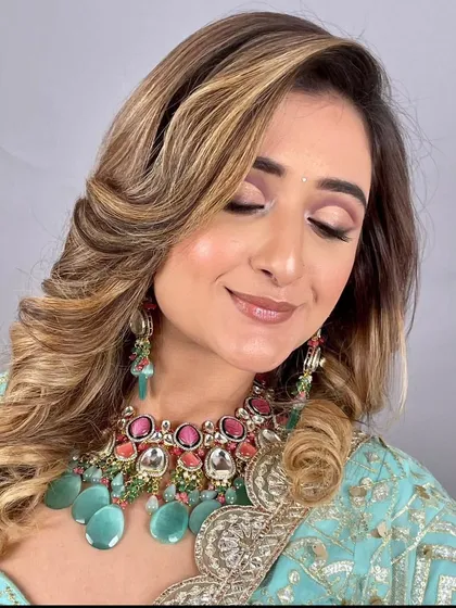 A model wearing a pastel blue outfit with a unique Kundan necklace featuring pink and sea-green stones. This is a great option for a sangeet or mehendi event.