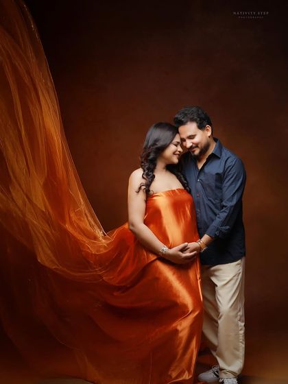 A romantic couple's portrait with a flowing orange gown. The fabric toss creates a beautiful, dynamic frame around the couple.