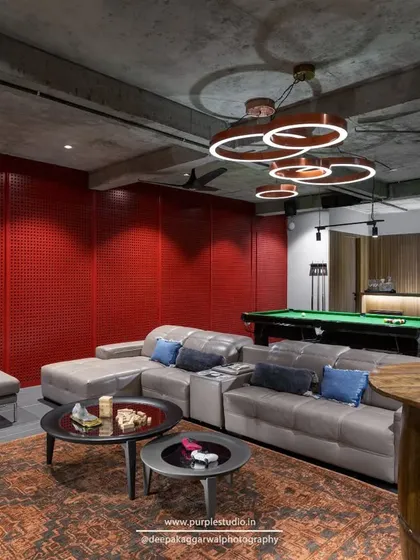 An entertainment lounge designed for fun and relaxation, complete with a pool table and comfortable seating. The bold red acoustic wall adds a vibrant, energetic feel to this basement space.