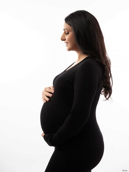 A silhouetted profile against a white background, emphasizing the beautiful curve of her bump. This is a classic and beloved maternity shot.