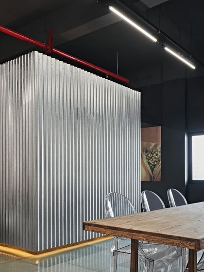 This meeting room for a luxury showroom features walls and partitions made of corrugated tin. It's a raw, industrial, and edgy space that is as bold as the ideas discussed within it.