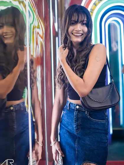 A guest smiling and posing by the colorful, neon-lit entrance.