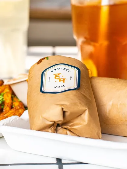 A shot of a wrapped roll from Project Hum, perfect for takeaway. The focus on the branded packaging is great for building brand recognition.