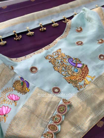 A light blue blouse featuring a hand-painted Tanjore-style peacock, combined with lotus embroidery.