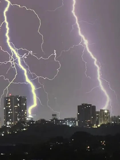 Another perspective of the urban thunderstorm, showing the contrast between the dark silhouettes of the buildings and the bright, chaotic energy of the lightning.