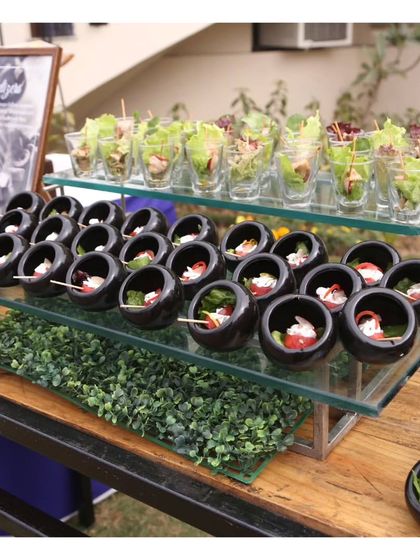 A tiered display of assorted canapés, including caprese skewers in small black bowls and fresh salad cups. This demonstrates our ability to create diverse and attractive appetizer stations.