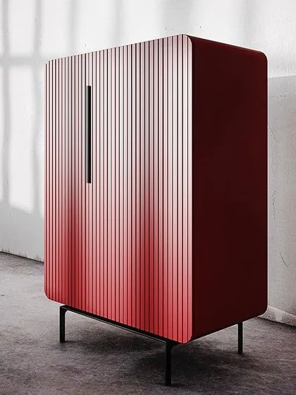 The silhouette of this cabinet gently bends over the corner, while the fluted facade creates a uniform pattern. Shown here in a striking ombré red, this piece features soft-closing mechanisms for maximum comfort and no slamming noise.