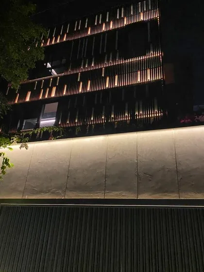 At night, the facade of this Koramangala home comes alive with integrated lighting, highlighting the vertical wooden slats and creating a warm, inviting, and dynamic exterior.