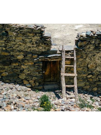 A rustic wooden ladder leans against an old stone wall, a detail of the timeless architecture in the region.