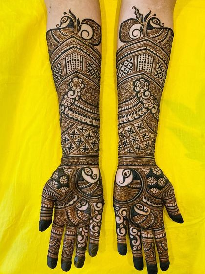 Graceful peacock motifs are the centerpiece of this design, surrounded by intricate jaali (net) and floral patterns that extend up the arm.